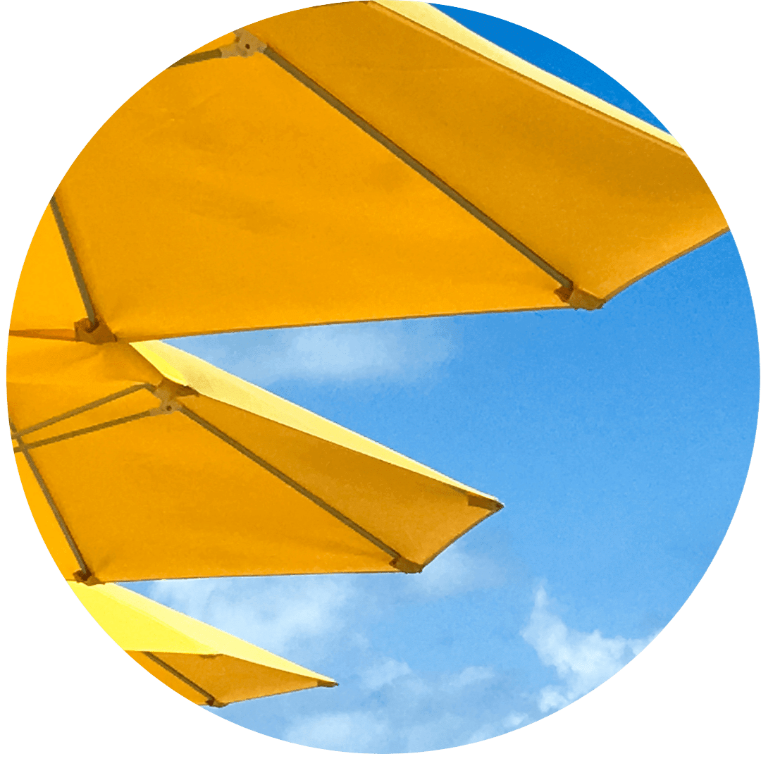 Close-up of yellow umbrellas against a bright blue sky with a few clouds. The vibrant yellow contrasts with the sky, creating a summery vibe.